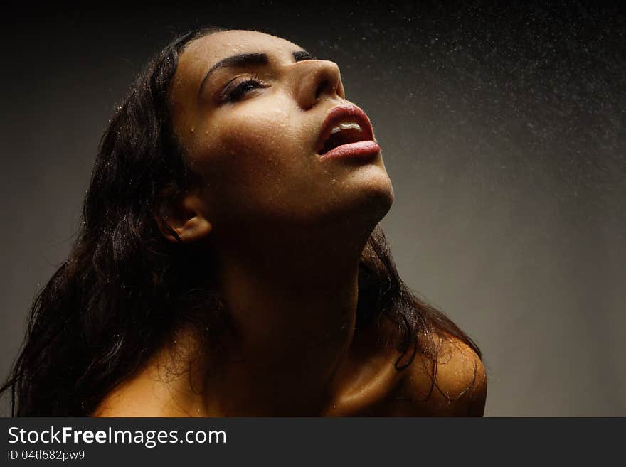 Portrait of a girl on a dark background. Water on her face.