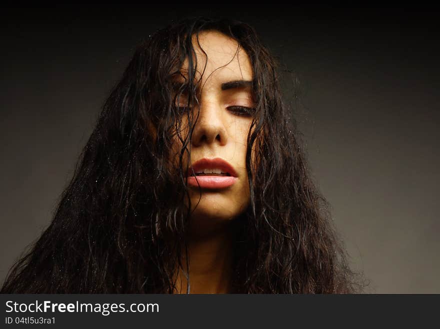 Portrait of a girl with wet hair and water on her face. Dark background.