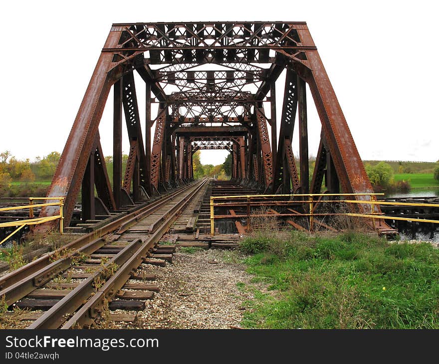 Old abandoned railroad bridge with rusty girders and tracks.  White space for copy or text. Old abandoned railroad bridge with rusty girders and tracks.  White space for copy or text.