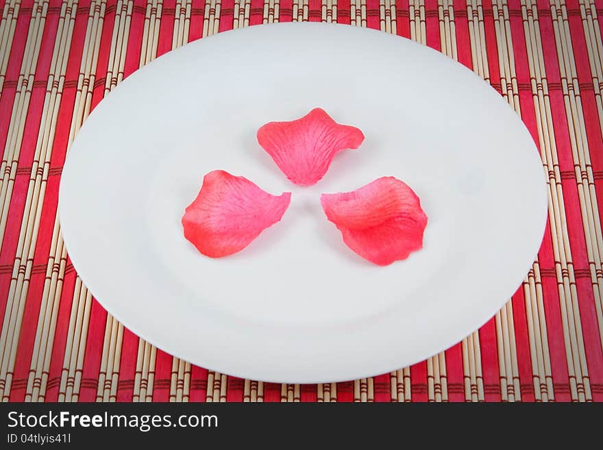 Arrangement of rose petals on a plate. On a red napkin.