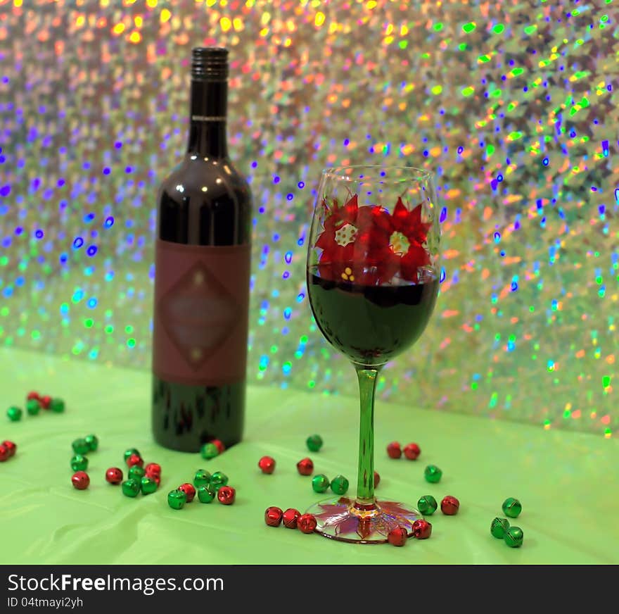 Red wine in a holiday wine glass with bottle of wine in back ground