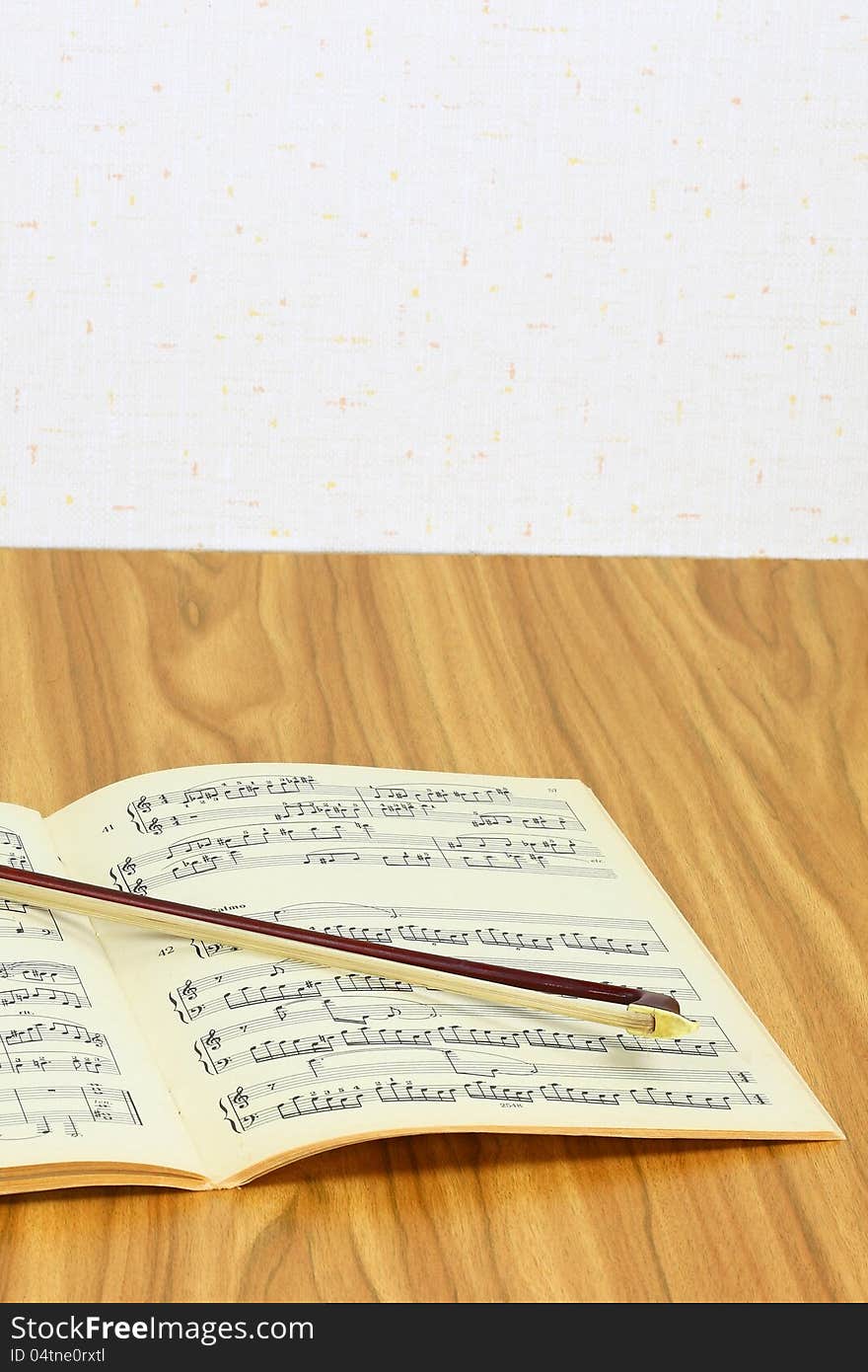 Violin bow over music sheet lie on the table top. Violin bow over music sheet lie on the table top