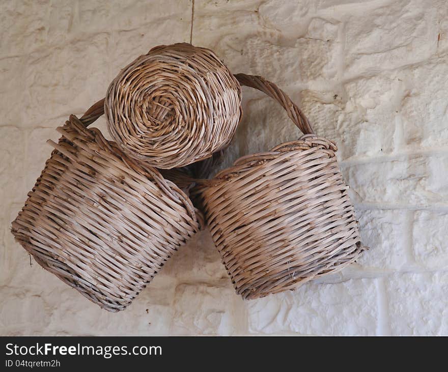 Three old baskets weaved from willow rods hanging on a wall. Three old baskets weaved from willow rods hanging on a wall