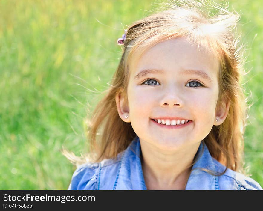 Outdoor portrait of smiling little girl on the meadow