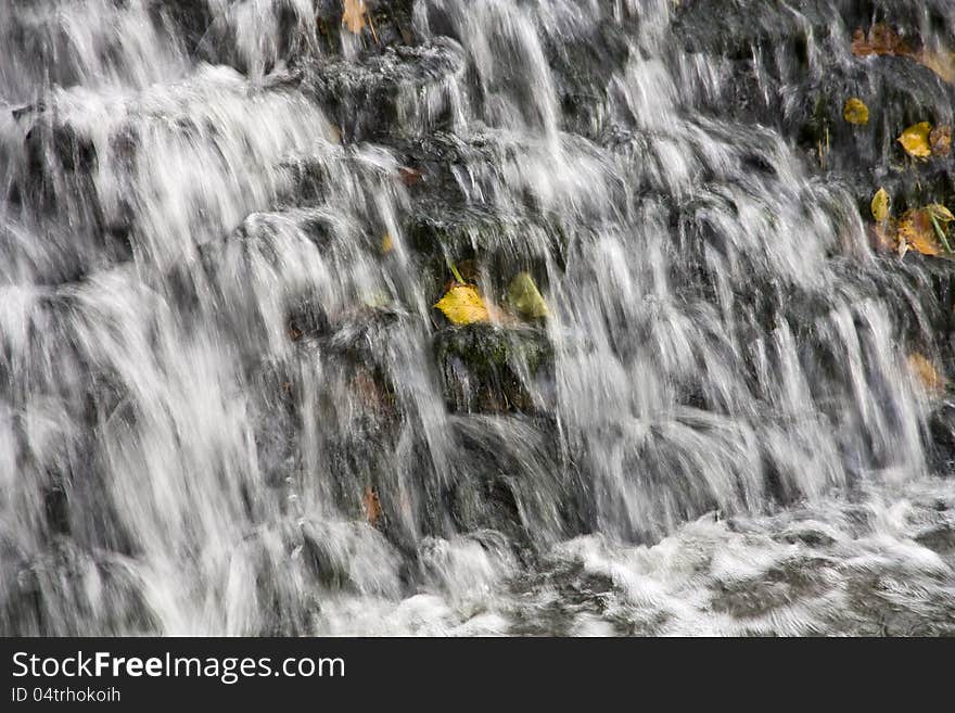 Yellow leaf on a rock in the middle of the waterfall. Yellow leaf on a rock in the middle of the waterfall