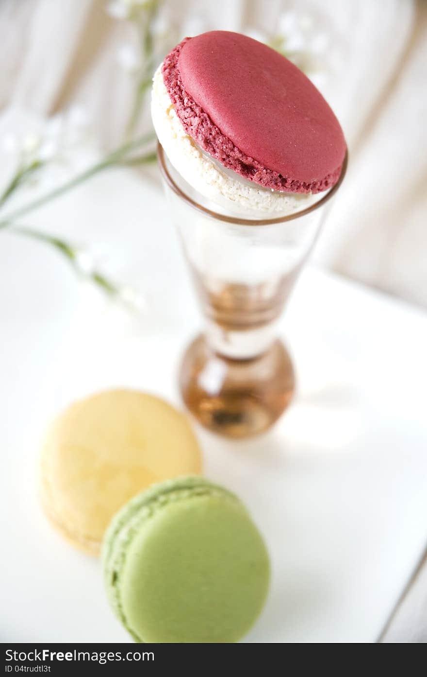 Close up pink macaron on glass with macarons on plate