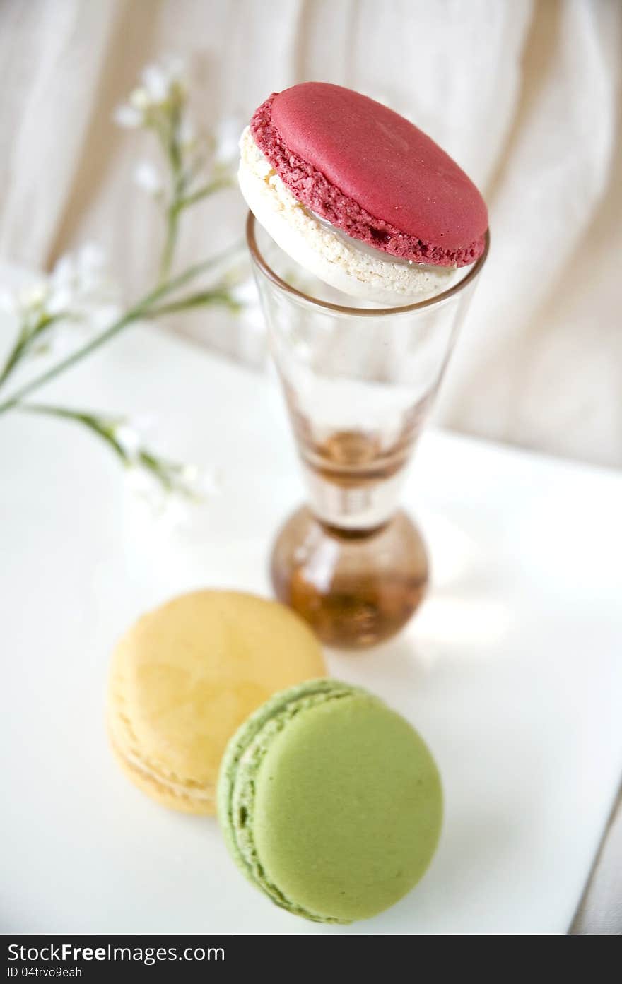 Macarons on plate with pink macaron on pink glass. Macarons on plate with pink macaron on pink glass