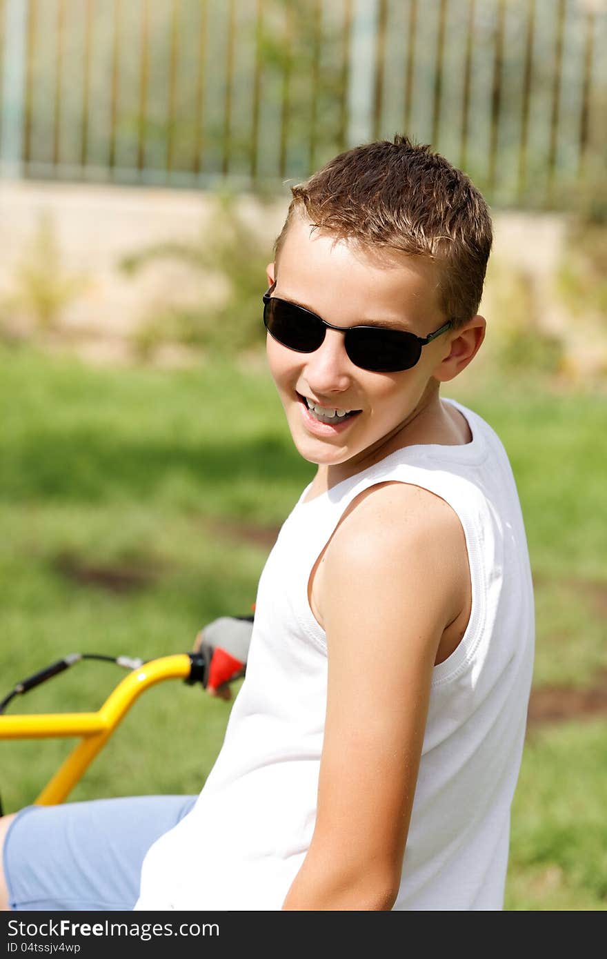 Boy in glasses on a bike outside in the summer