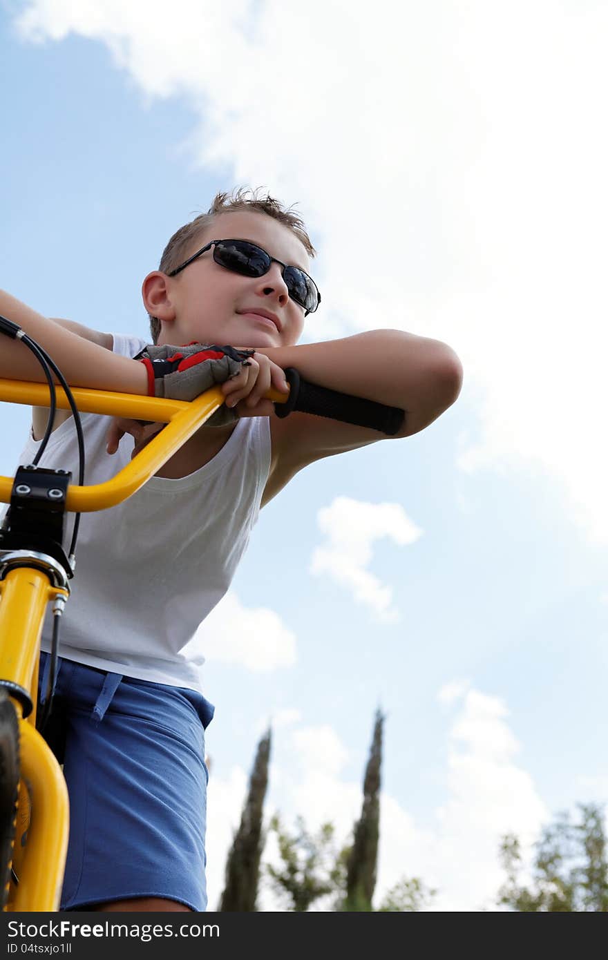 Pretty boy on a bike outside in the summer day