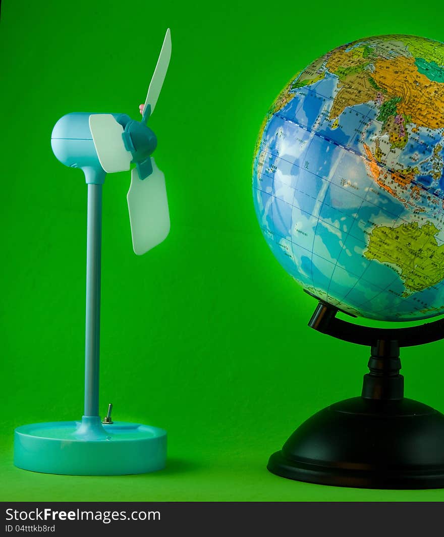 Wind turbine model and globe on green background. Wind turbine model and globe on green background