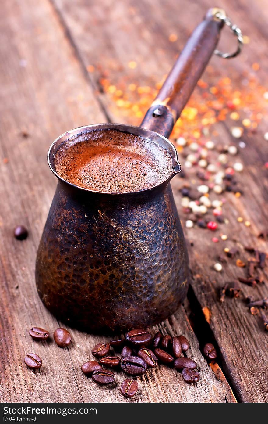 Coffee beans and vintage cezve on a wood surface