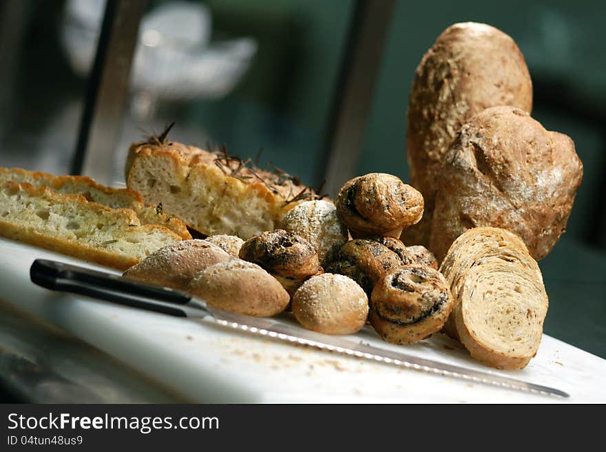 Selection of freshly made and sliced bread. Rosemary focaccia, rye bread, black olive rolls, sour dough loaf. Bread basket with white linen in the background . Shallow DOF. Selection of freshly made and sliced bread. Rosemary focaccia, rye bread, black olive rolls, sour dough loaf. Bread basket with white linen in the background . Shallow DOF