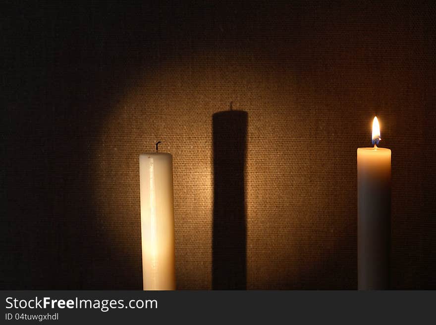 Extinguished and lighting candles with long shadow against canvas background. Extinguished and lighting candles with long shadow against canvas background