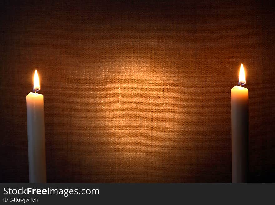 Pair of lighting candles against canvas background. Pair of lighting candles against canvas background