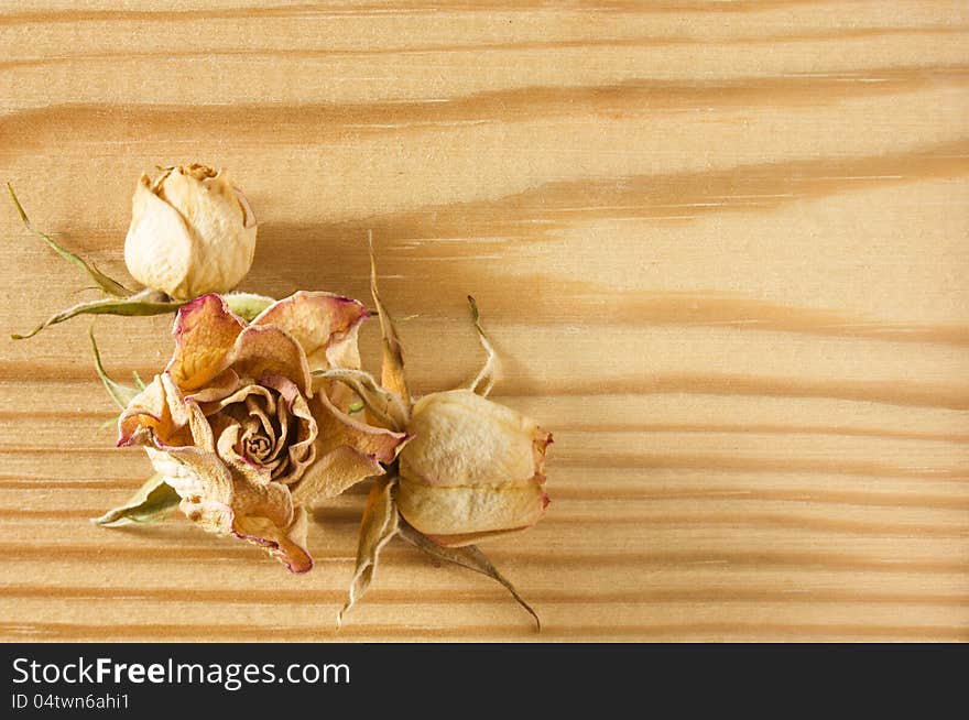 Dry rose flowers on rough wooden table