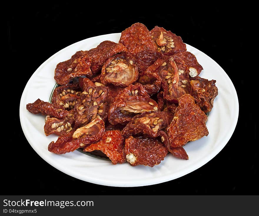 Dry tomatoes on white plate isolated over black background. Dry tomatoes on white plate isolated over black background