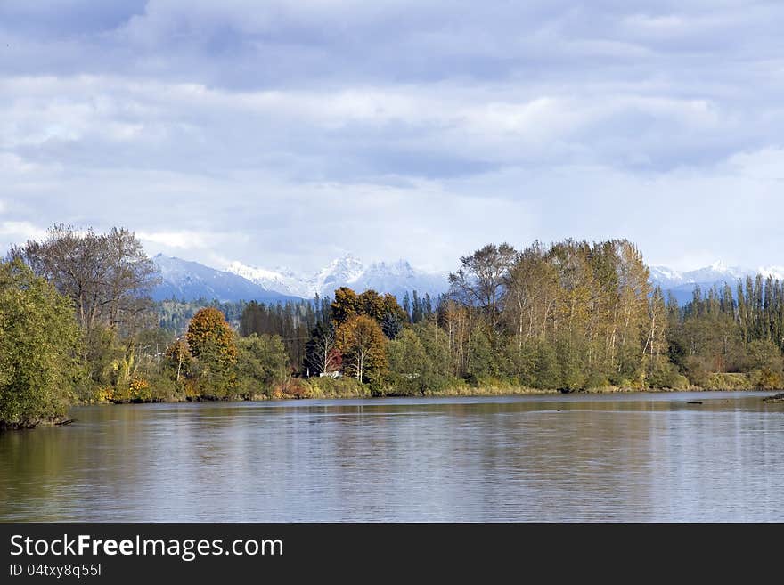 Beautiful fall colors of Snohomish River with snow mountains in distance, Washington State, USA. Beautiful fall colors of Snohomish River with snow mountains in distance, Washington State, USA