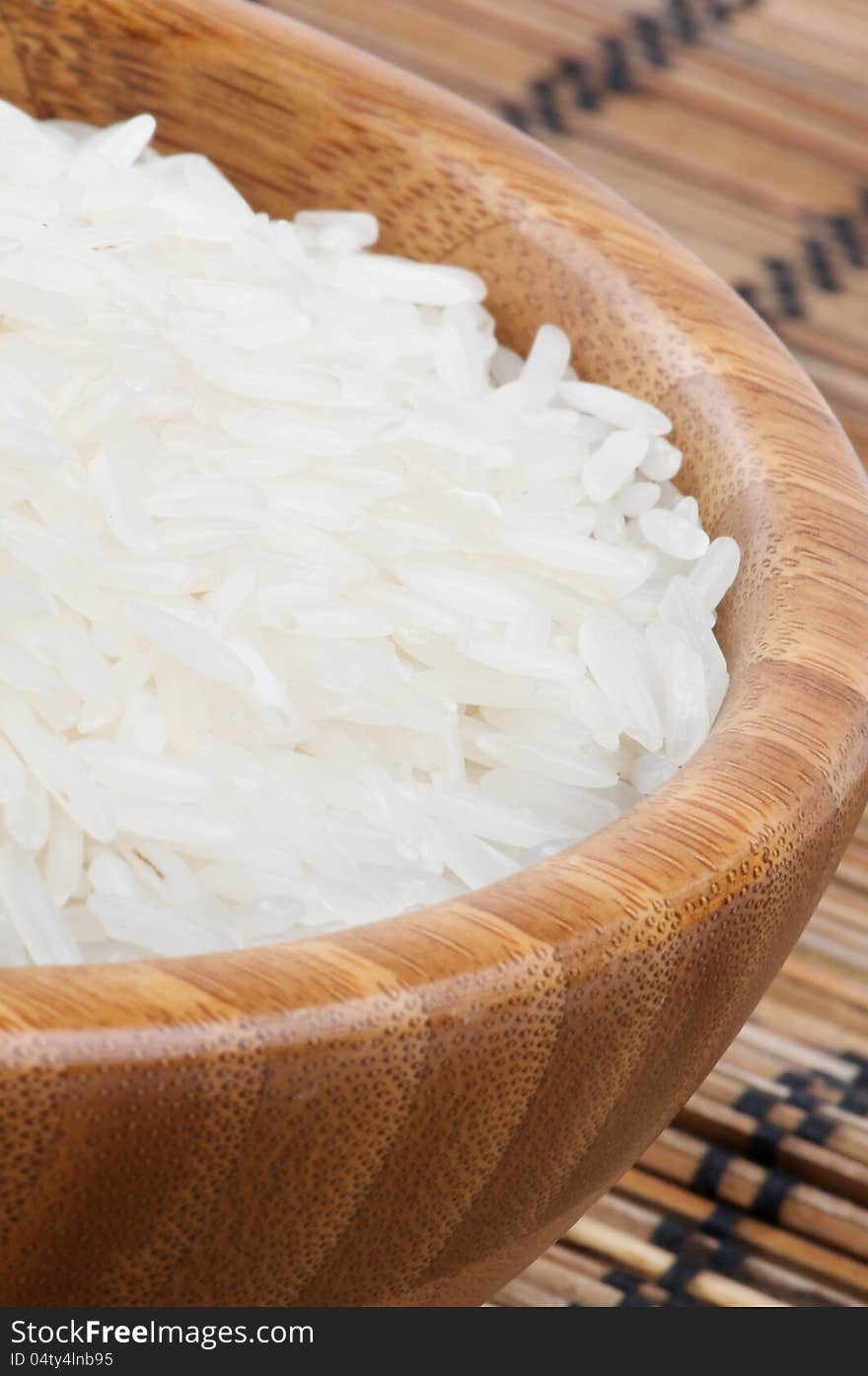 Perfect White Rice in Wooden Bowl closeup on Straw mat background