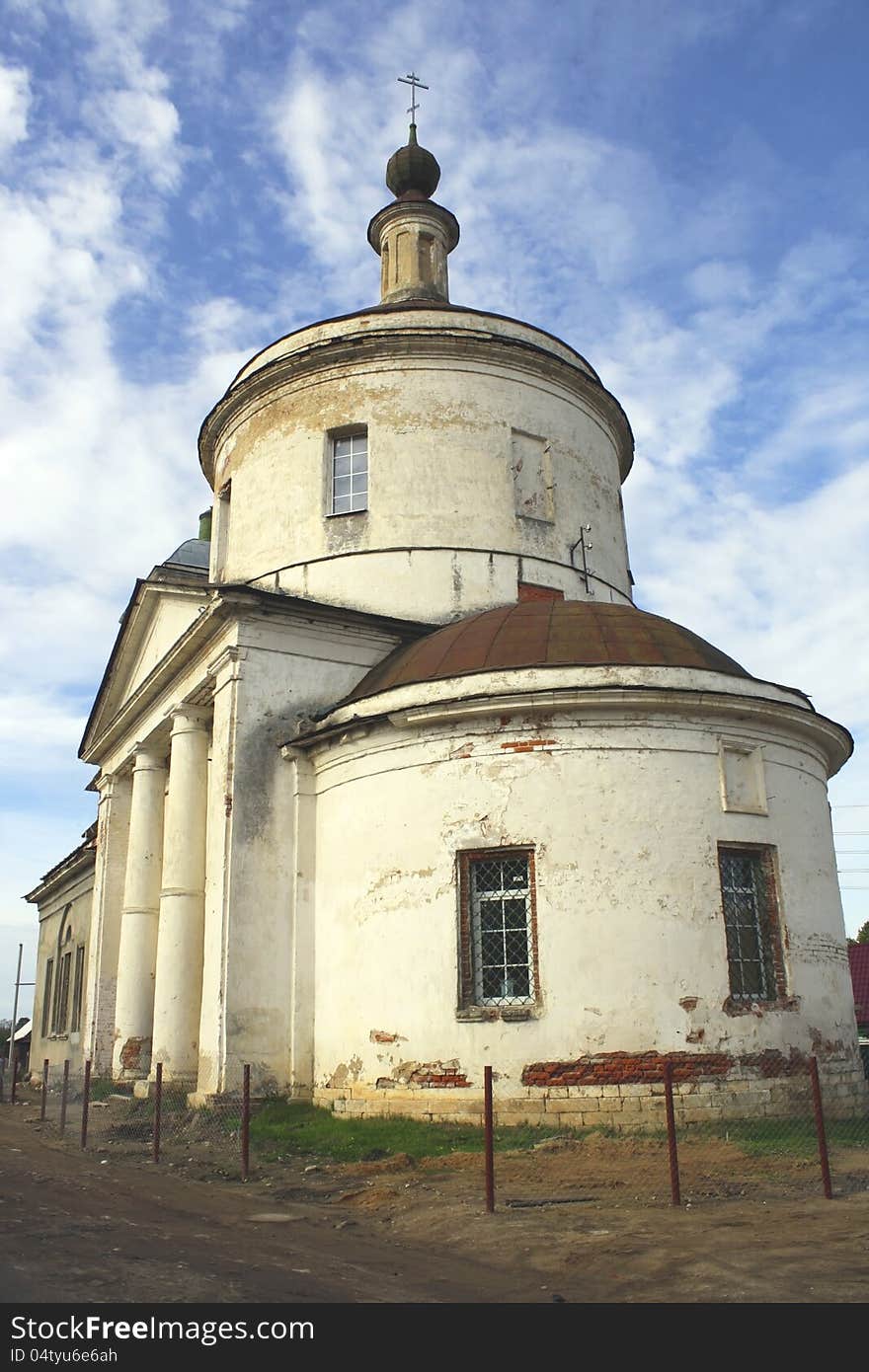 Photo of ancient Russian white church with a dome and columns against blue sky with clouds. Photo of ancient Russian white church with a dome and columns against blue sky with clouds