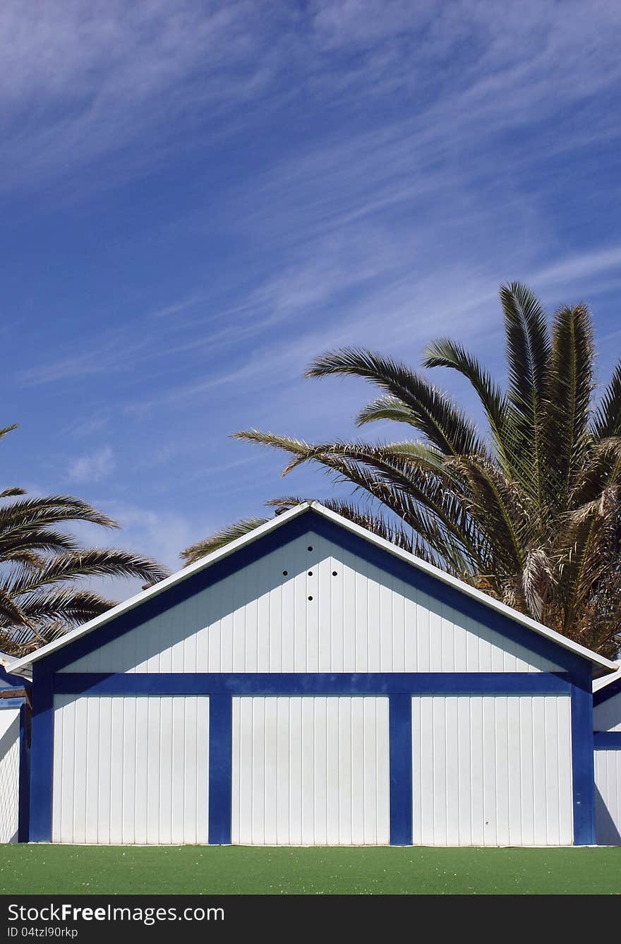 Bathing hut with palmas trees over blue sky