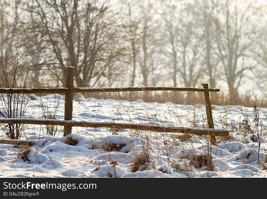 Winter fence with snow and grass around