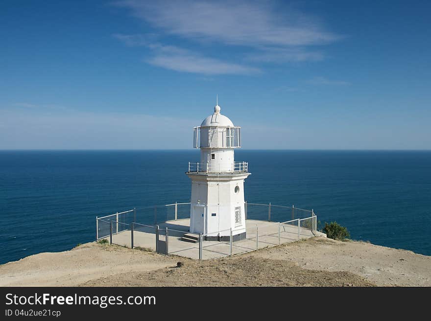 Lighthouse by the sea on a background of blue sky