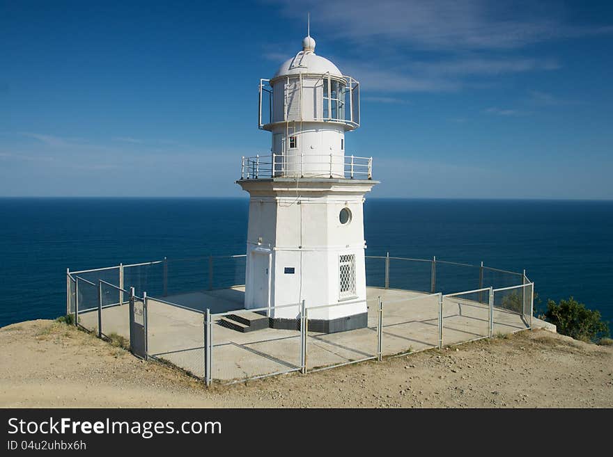 Lighthouse by the sea on a background of blue sky