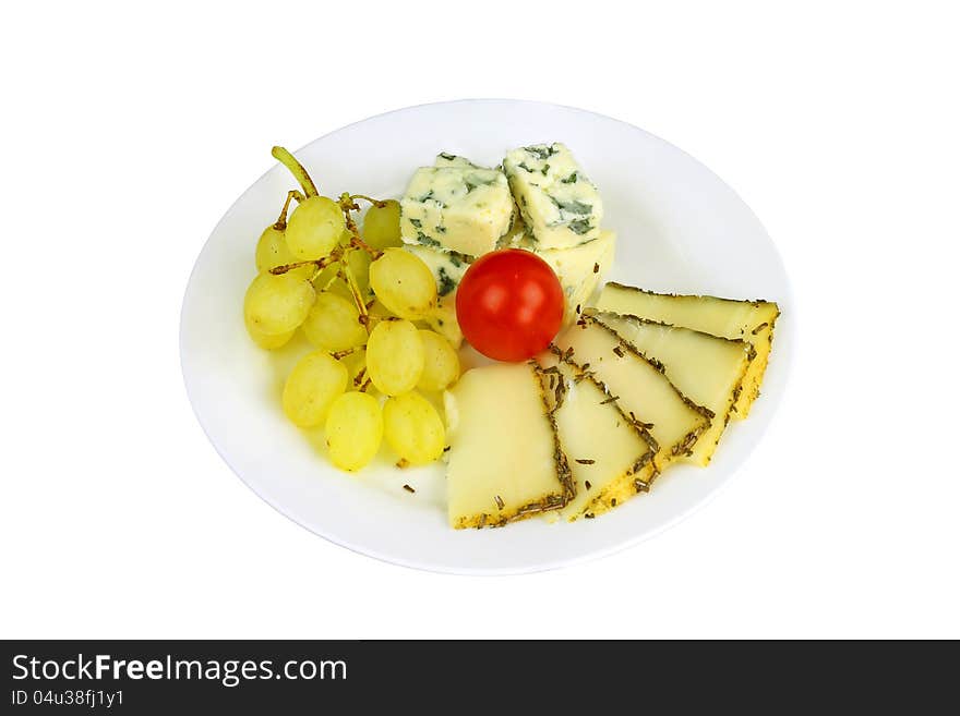 Blue cheese and piquant cheese with bunch of yellow grapes and small red tomato on a plate isolated on white. Blue cheese and piquant cheese with bunch of yellow grapes and small red tomato on a plate isolated on white