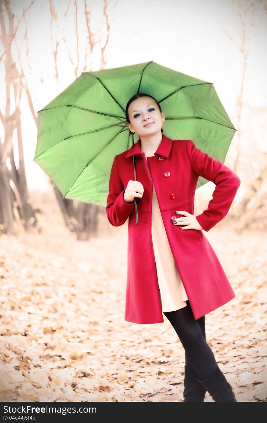 Pretty girl in red coat with umbrella in autumn