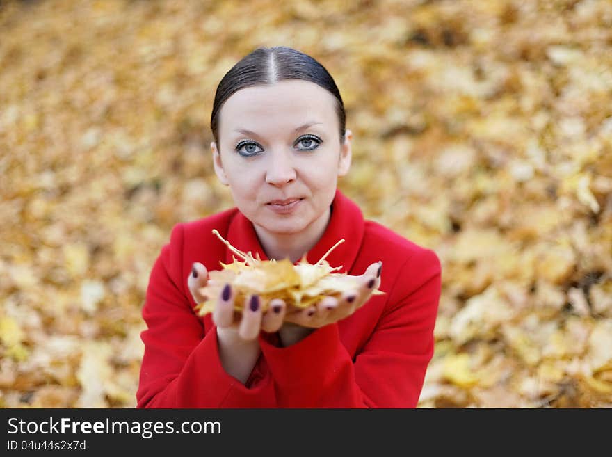 Pretty girl in red coat with leaves