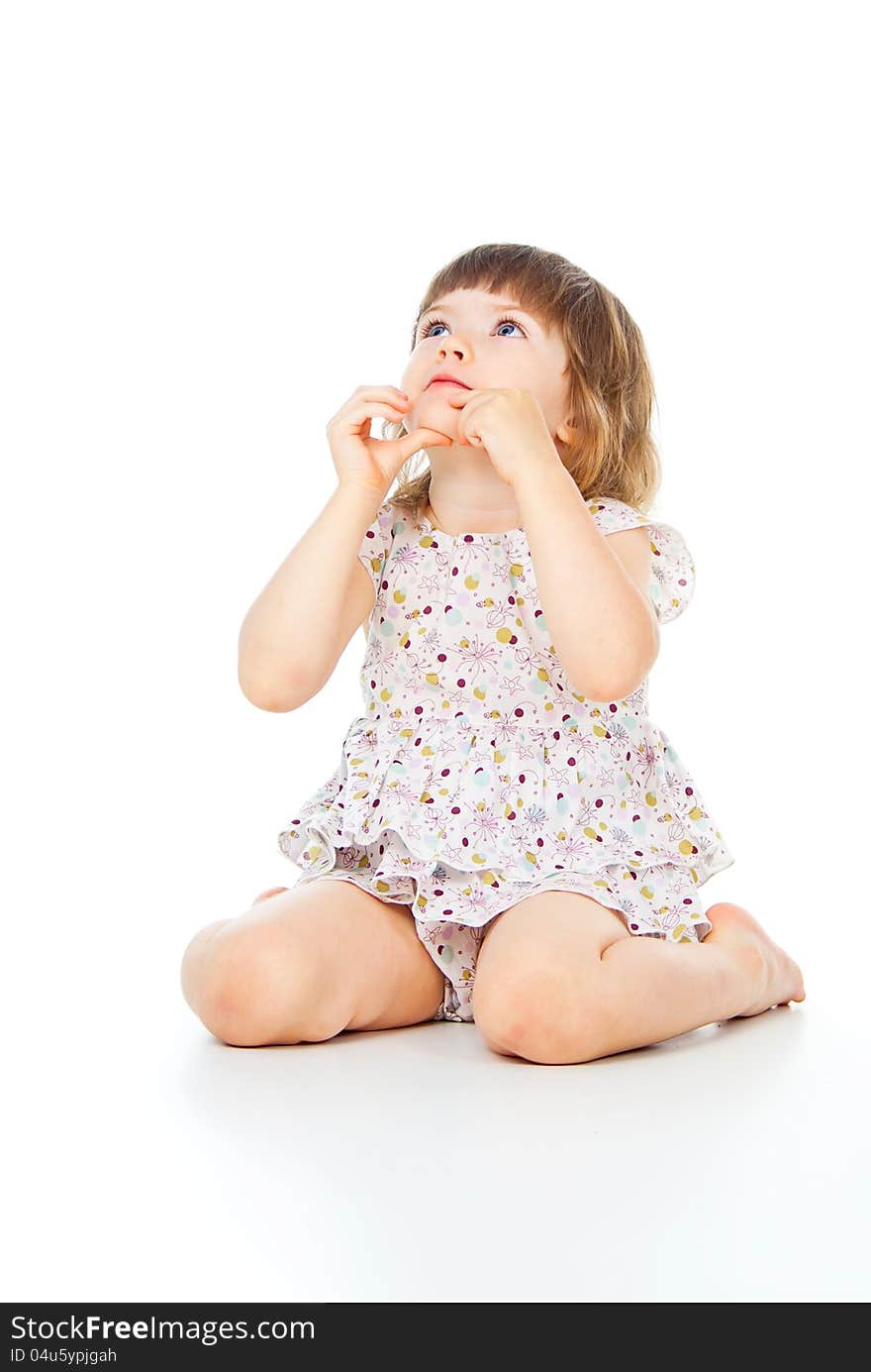 Sits a beautiful little girl in a dress