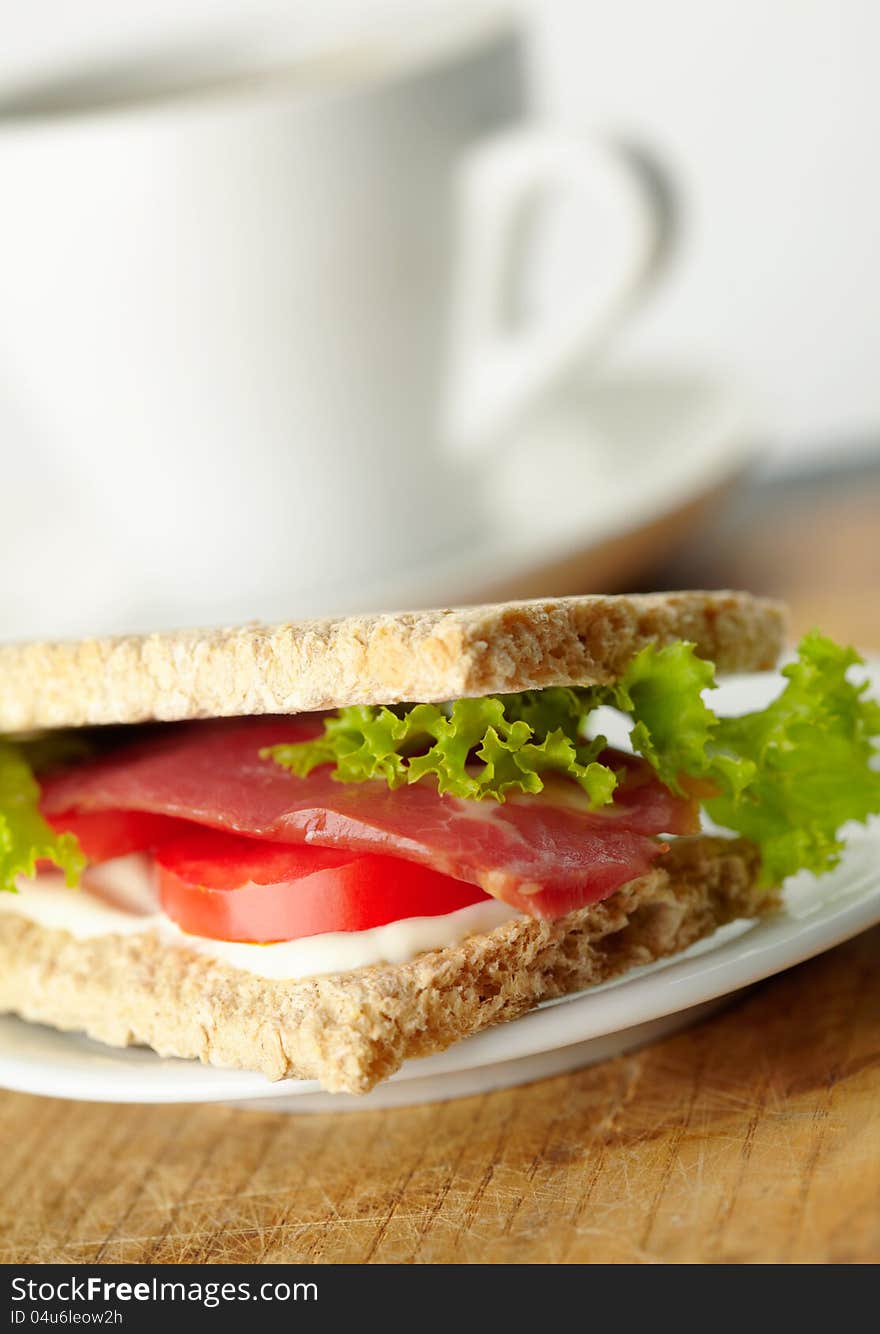 Homemade sandwich with bacon, tomato, rukola and mayonnaise on whole-grain bread