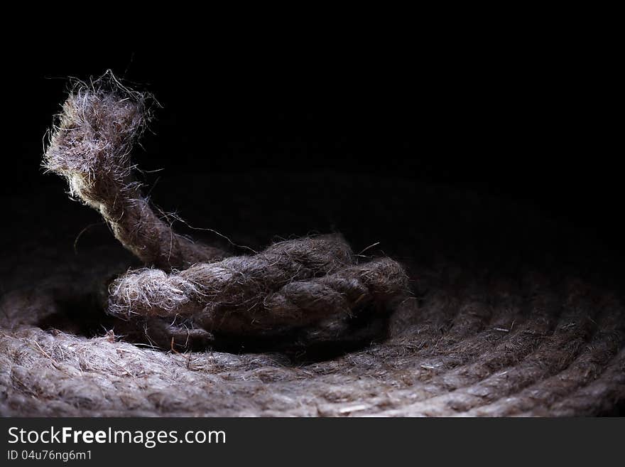 Skein of old hemp rope on dark background with free space for text