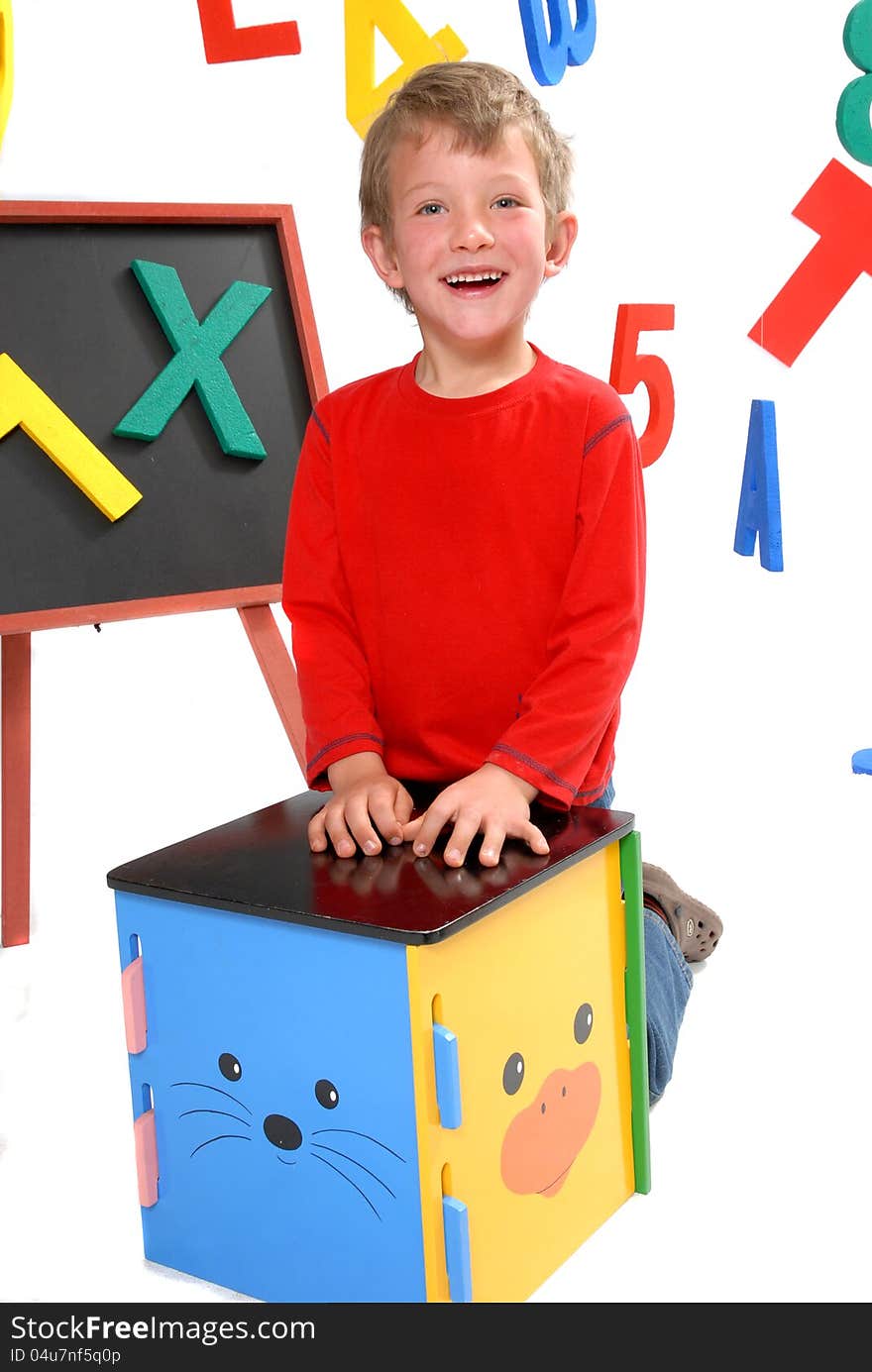 Happy young boy in preschool on isolated white background with bright letters and numbers. Happy young boy in preschool on isolated white background with bright letters and numbers