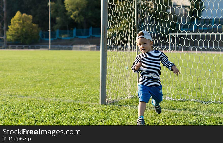 Little boy running on a soccer field protecting the goalposts as he has fun enjoying his freedom