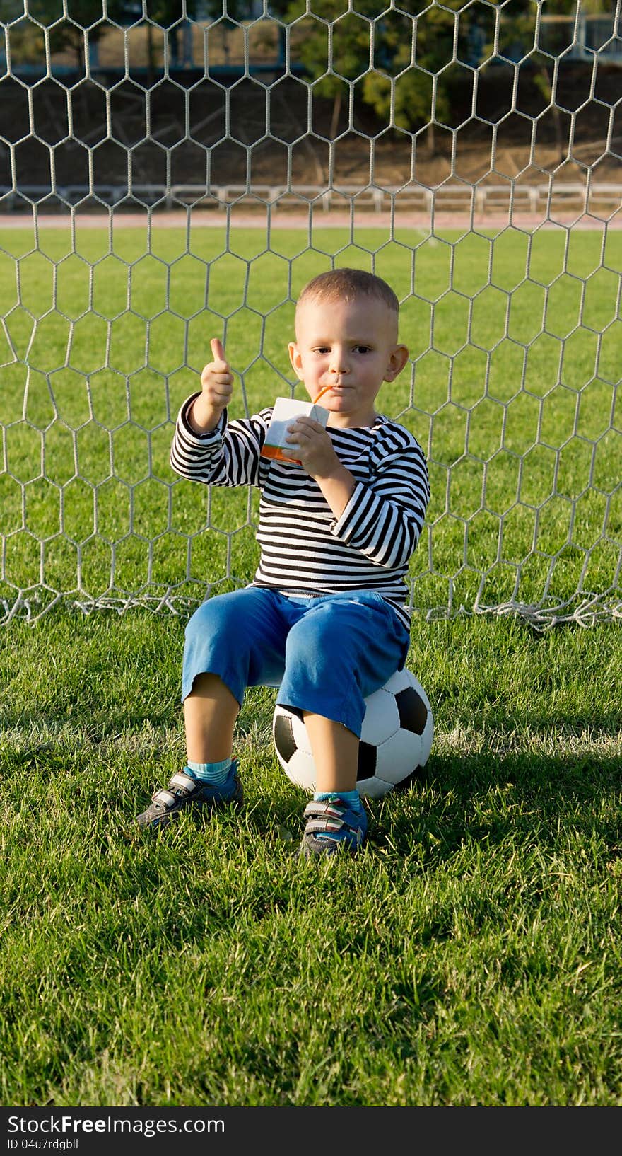 Small Boy Sitting On Soccer Ball