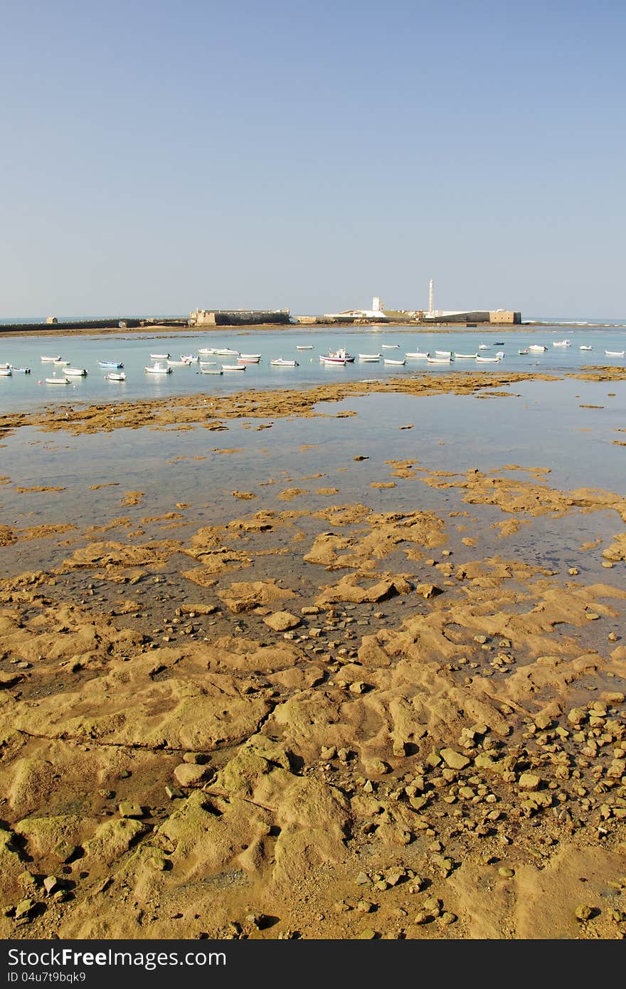 Low tide at dusk in the bay of Cadiz, Spain, with the castle of St Sebastian on the background. Low tide at dusk in the bay of Cadiz, Spain, with the castle of St Sebastian on the background