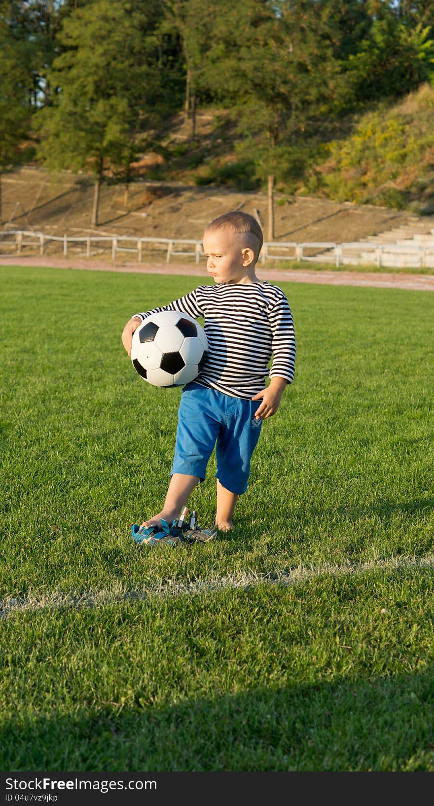 Small boy waiting with his soccer ball