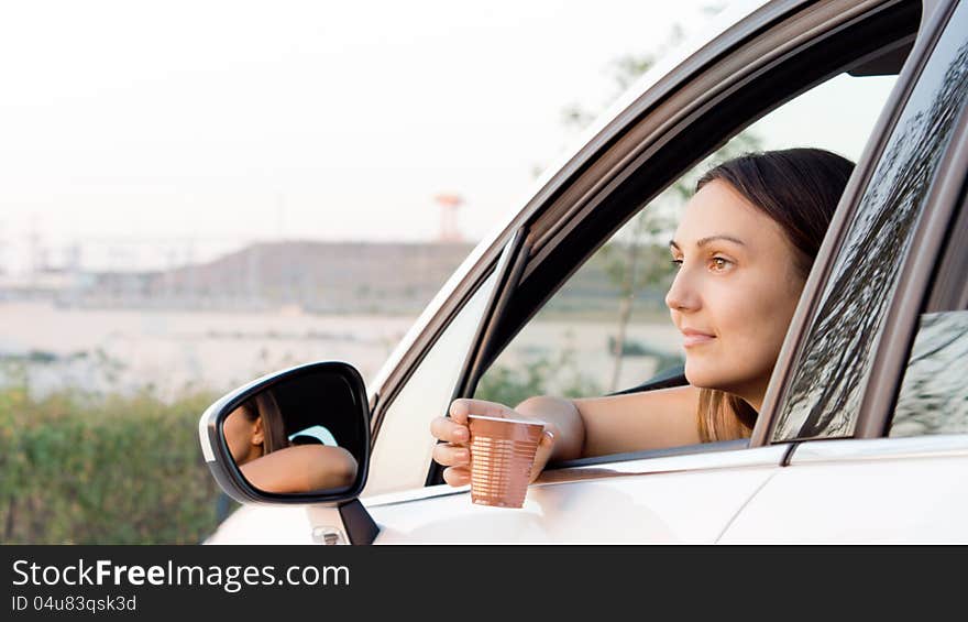 Woman sitting in car with a drink