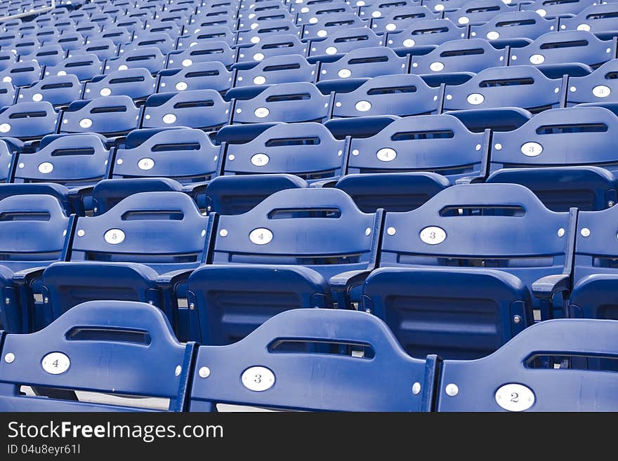 Rows of empty blue numbered stadium or arena seating. Rows of empty blue numbered stadium or arena seating