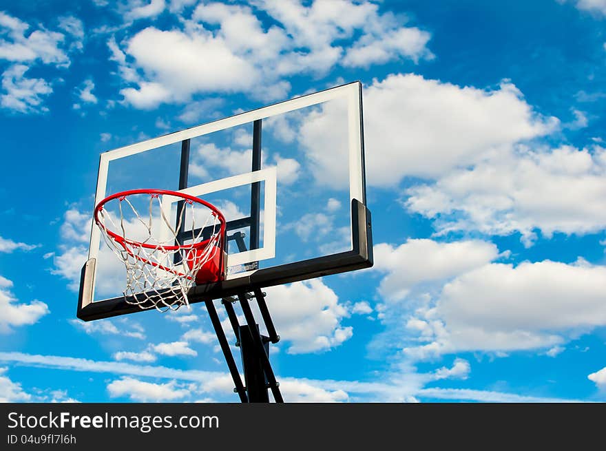 A basketball hoop and backboard against a cloudy background. A basketball hoop and backboard against a cloudy background