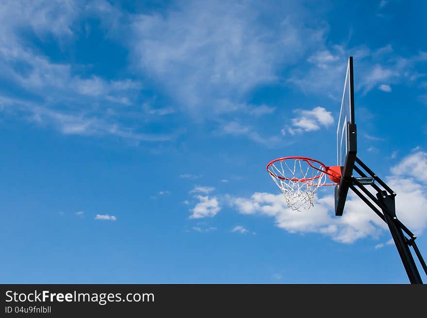 A basketball hoop and backboard against a cloudy background. A basketball hoop and backboard against a cloudy background