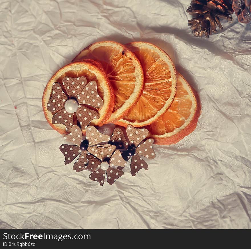 On a white table are dried orange segments and paper flowers. On a white table are dried orange segments and paper flowers