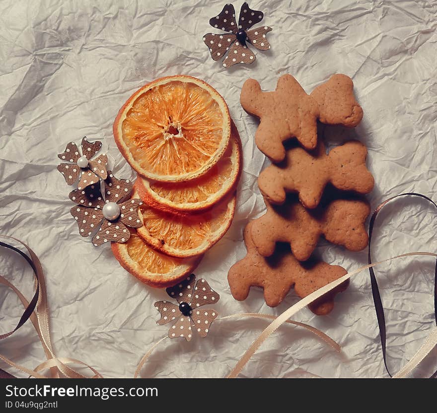 On a white table are dried orange segments and Christmas cookies. On a white table are dried orange segments and Christmas cookies