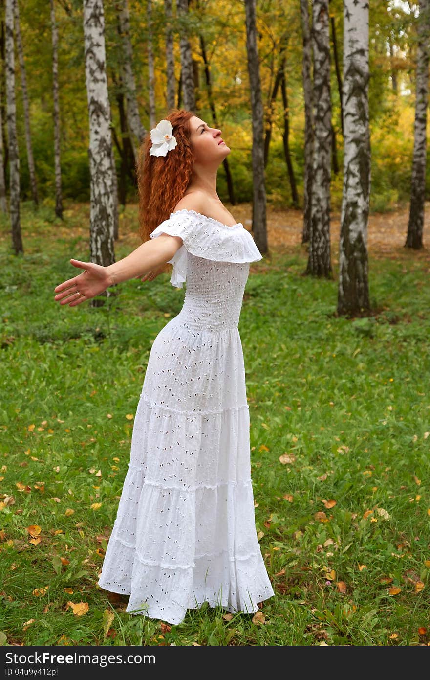 Beautiful red-haired young woman, wearing in white dress or the bride and decoration in form of flower on her head looking up, arms. as if flying. The concept of happiness and freedom. Beautiful red-haired young woman, wearing in white dress or the bride and decoration in form of flower on her head looking up, arms. as if flying. The concept of happiness and freedom.