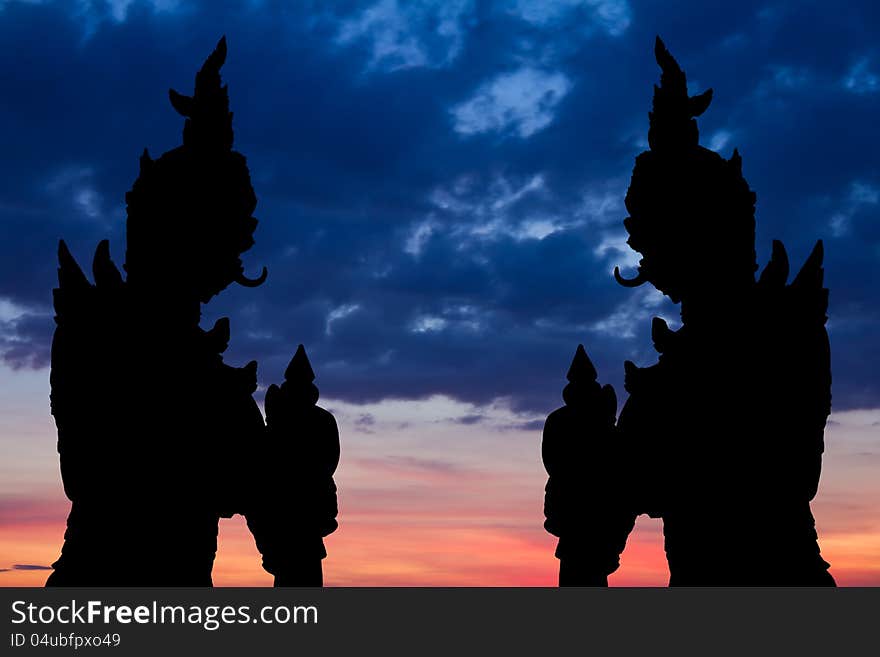 Silhouette by two giant statues standing tall on the background of a beautiful sky. Silhouette by two giant statues standing tall on the background of a beautiful sky.