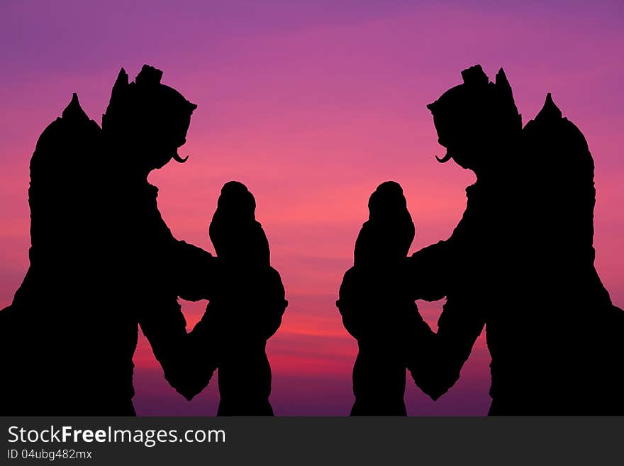 Silhouette by two giant statues standing tall on the background of a beautiful sky. Silhouette by two giant statues standing tall on the background of a beautiful sky.