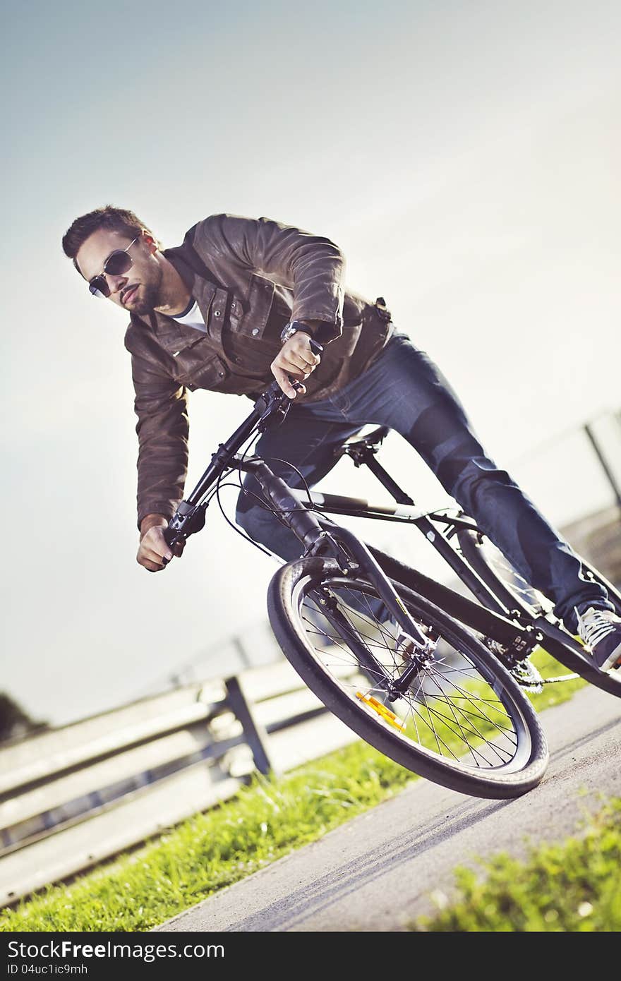 Young man riding a bicycle to work in the leather jacket