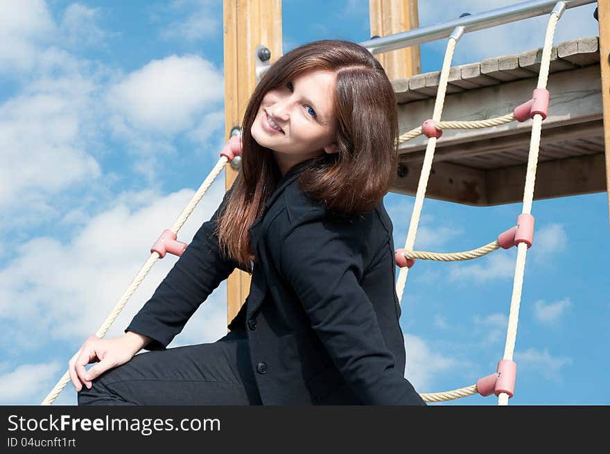 Young business woman sitting on ladder and smiling.