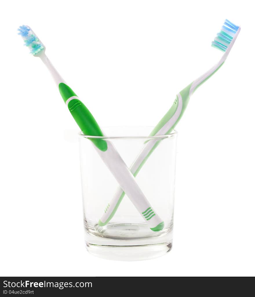 Two green  toothbrushes in a clear glass. Two green  toothbrushes in a clear glass